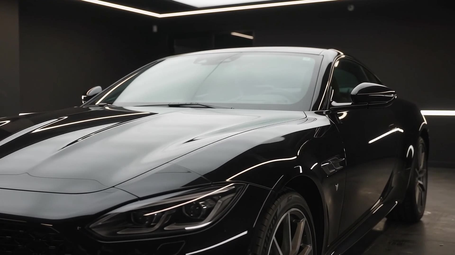 Polished black sports coupe in a dark professional detailing studio